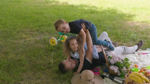 Pappa stenar på marken med sin dotter och son i slow motion — Stockvideo