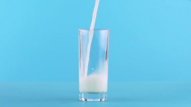 Süt soğuk içecek içki pooring Studio düşük cam mavi arka plan içine, ağır çekim yakın çekim vurdu