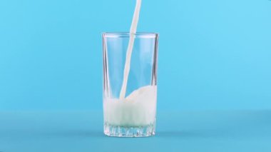 Süt soğuk içecek içki pooring Studio iş parçacıklı cam mavi arka plan içine, ağır çekim yakın çekim vurdu