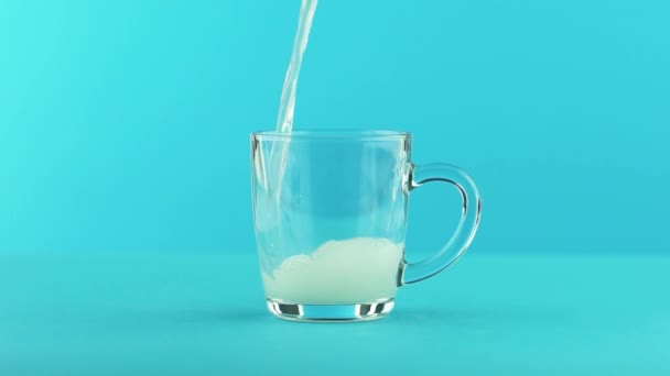 Slow motion close-up shot of fruit fizzy lemonade soda cold beverage drink pooring into glass mug with handle blue background in studio — Stock Video