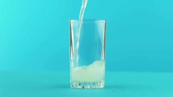 Zwolnionym tempie zbliżenie z owoców gazowane lemoniada soda zimne napoje napój pooring w gwintowane szkło niebieskie tło w studio — Wideo stockowe