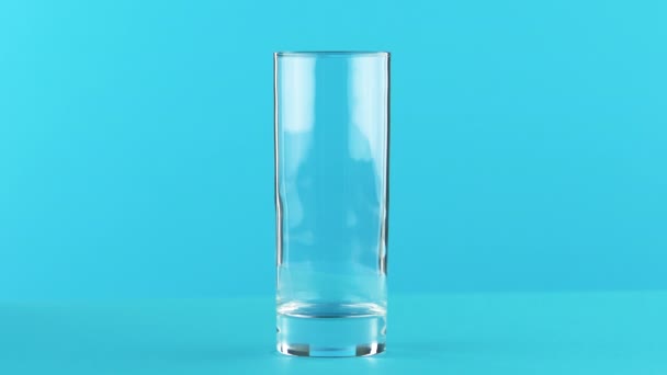 4 k close-up shot van melk koud drankje drinken massasprint in in glas blauwe achtergrond in de studio — Stockvideo