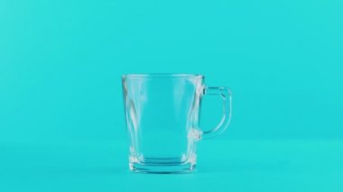 Cam Kupa Studio kolu mavi arka plan ile içine pooring süt soğuk içecek 4 k yakın çekim çekim içecek