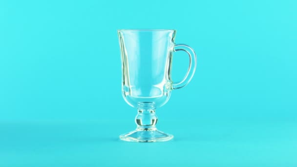 4K primer plano de fruta jugo multifruta bebida fría bebida pooring en latte vidrio taza fondo azul en estudio — Vídeos de Stock