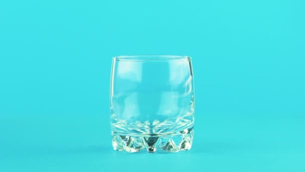 4k Nahaufnahme von Milch Kaltgetränk Drink strömt in kleine schöne Glas blauen Hintergrund im Studio — Stockvideo