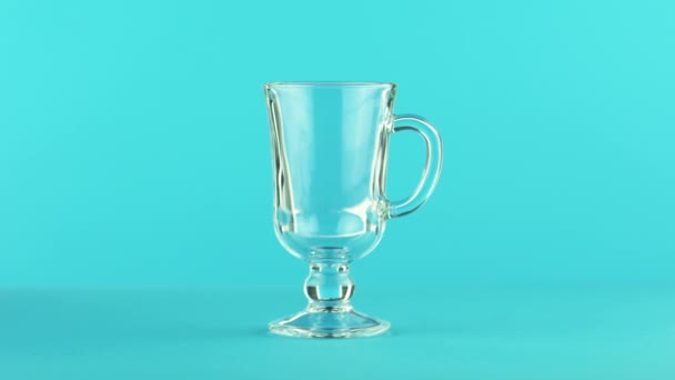 4 k κοντά shot της ανθρακούχα πορτοκαλί κρύο ρόφημα φρούτων ποτό pooring με latte γυαλί κούπα μπλε φόντο στο studio — Αρχείο Βίντεο