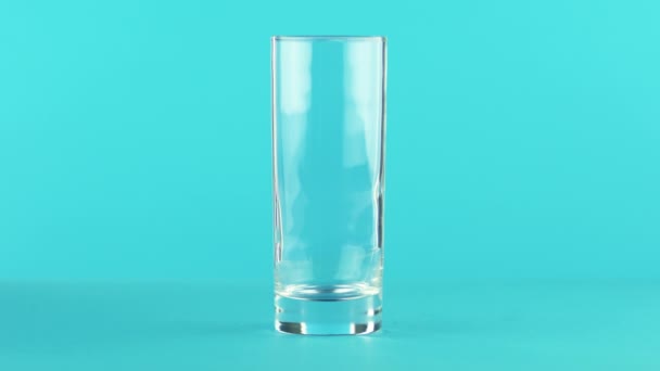 フルーツ炭酸オレンジ冷飲料の 4 k のクローズ アップ ショット飲むガラスの青い背景に pooring スタジオ — ストック動画