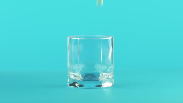 4K close-up shot de fruta bebida gelada laranja efervescente em vidro baixo com facetas de fundo azul em estúdio — Vídeo de Stock