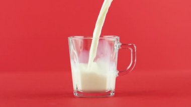 Soğuk günlük süt soğuk içecek içki pooring cam kupa kolu kırmızı arka plan ile içine yavaş hareket yakın çekim çekim