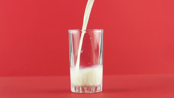 Câmera lenta close-up tiro de fustigada de bebida de bebida fria fria diário leite no fundo de rosca vidro vermelho no studio — Vídeo de Stock