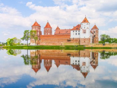 Mir, Belarus. Kale karmaşık Mir göl üzerinde güneşli gün mavi gökyüzü arka plan ile yansıtılır. Eski Ortaçağ kuleler ve unesco Dünya Kültür Mirası Listesi'ne geleneksel kaleden duvarları