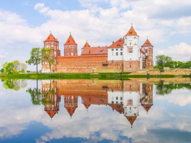 Mir, Belarus. Kale karmaşık Mir göl üzerinde güneşli gün mavi gökyüzü arka plan ile yansıtılır. Eski Ortaçağ kuleler ve unesco Dünya Kültür Mirası Listesi'ne geleneksel kaleden duvarları