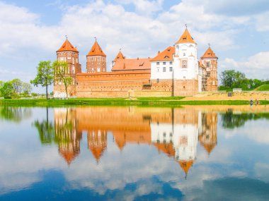 Mir, Belarus. Kale karmaşık Mir göl üzerinde güneşli gün mavi gökyüzü arka plan ile yansıtılır. Eski Ortaçağ kuleler ve unesco Dünya Kültür Mirası Listesi'ne geleneksel kaleden duvarları
