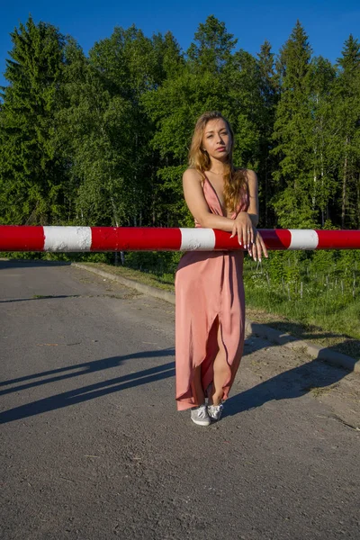 Kırmızı bariyer ve gülümseme tarafından poz uzun mercan elbiseli Genç ince güzel kız