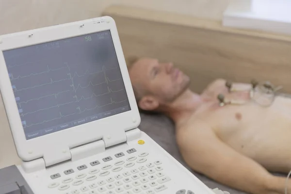 Médico de seguimiento de la vida con equipo de electrocardiograma que hace la prueba de cardiograma al paciente masculino en la clínica hospitalaria — Foto de Stock