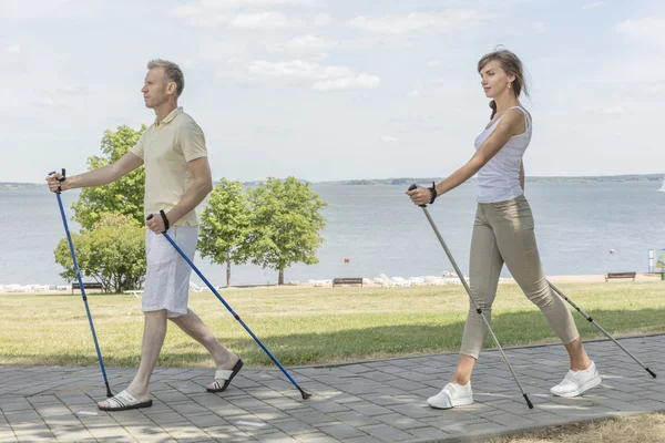 Young couple hiking in the nature nordic walking naer the lake — Stock Photo, Image