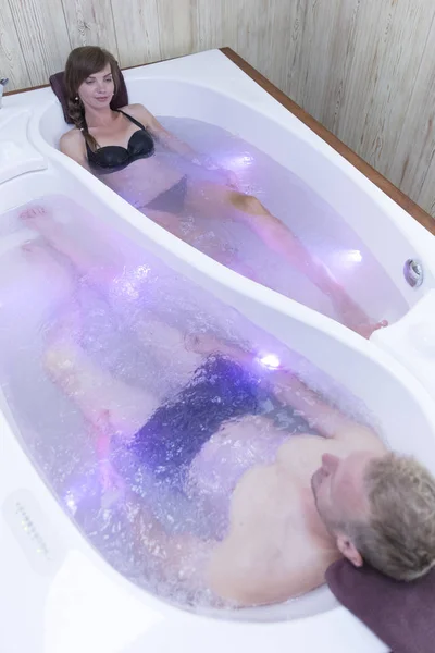 Unga lyckliga par njuter av bad i jacuzzin - par älskare på ett datum i Spa — Stockfoto