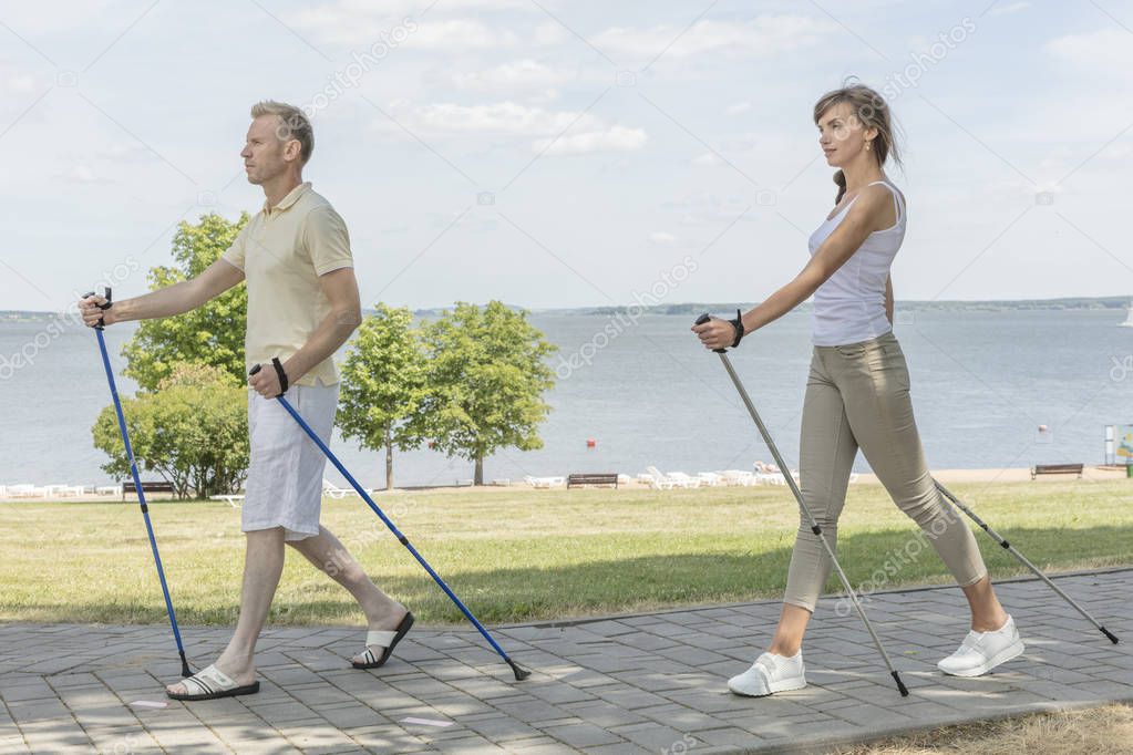 Young couple hiking in the nature nordic walking naer the lake