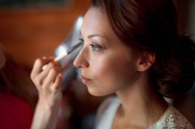 Makyaj yapma işlemi. Fırça ile çalışma modeli yüzünde makyaj sanatçısı. Güzellik salonu iç genç esmer kadın portresi. Cilde uygulanan sesi.