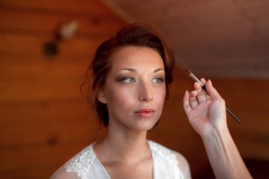 Makyaj yapma işlemi. Fırça ile çalışma modeli yüzünde makyaj sanatçısı. Güzellik salonu iç genç esmer kadın portresi