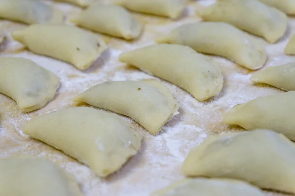 Traditionelle russische Speisenknödel oder Vareniki, Teig mit Fleisch oder anderen Füllungen, mit Mehl und Ei auf einem Tisch mit saurer Sahne, Pilzen und frischem Gemüse, Knoblauchsoße serviert. traditionell — Stockfoto