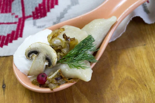 Traditional Russian food dumplings or vareniki, dough with meat or other stuffing, with flour and egg served on a table with sour cream, mushrooms and fresh vegetables, garlic sauce. traditional