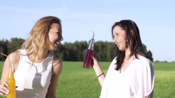 Lento tiro em movimento Duas meninas sexy adultos jovens beber de uma palha e rir coquetel de álcool tropical exótico ou suco de bebida fria ou refrigerante vermelho sabor de morango ou laranja e sabor ao ar livre no vestido em — Vídeo de Stock