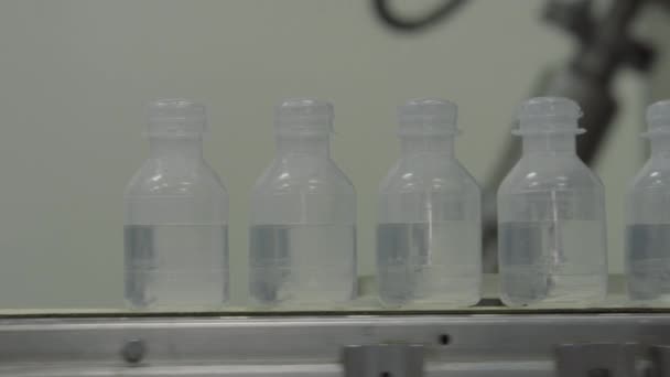 Bouteilles en plastique bouchées stérilisées avec médicament sur le convoyeur de la technologie Blow fill seal une technique de fabrication utilisée pour produire un récipient rempli de liquide sur une usine médicale ou alimentaire industrielle — Video