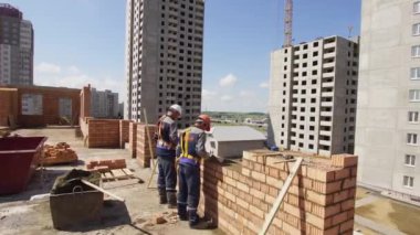 Minsk, Beyaz Rusya, 14 Ağustos 2018 - İnşaatçılar tuğladan bir apartman inşa ediyorlar. İşçi bir şantiyeye tuğla döşer. Brickwork sanayi şehir arka plan