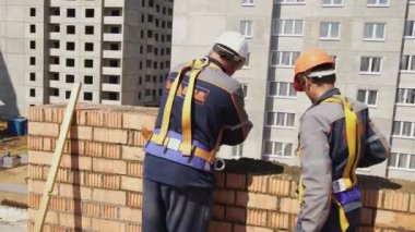 Minsk, Beyaz Rusya, 14 Ağustos 2018 - İnşaatçılar tuğladan bir apartman inşa ediyorlar. İşçiler bir şantiyeye tuğla döşerler. Tuğla sanayi