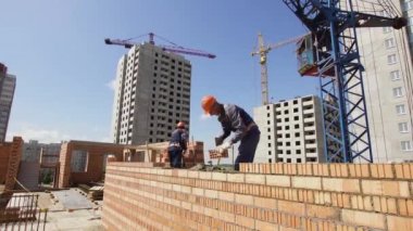 Minsk, Beyaz Rusya, 14 Ağustos 2018 - İnşaatçılar tuğladan bir apartman inşa ediyorlar. İşçi bir şantiyeye tuğla döşer. Tuğla sanayi