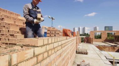 Minsk, Beyaz Rusya, 14 Ağustos 2018 - tuğladan bir apartman inşa. İşçi bir şantiyeye tuğla döşer. Tuğla sanayi