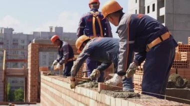Minsk, Beyaz Rusya, 14 Ağustos 2018 - İnşaatçılar tuğla inşa ediyor. İşçi bir şantiyeye tuğla döşer. Tuğla sanayi