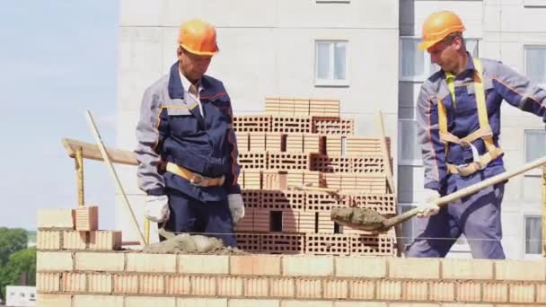 Minszk, Belorusszia, August 14 2018-a munkavállaló határozza meg a tégla egy építkezésen. Brickwork ipari. Építők épület egy bérház tégla. — Stock videók