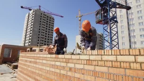Minszk, Belorusszia, August 14 2018-a munkavállaló határozza meg a tégla egy építkezésen. Ipari falazatok — Stock videók