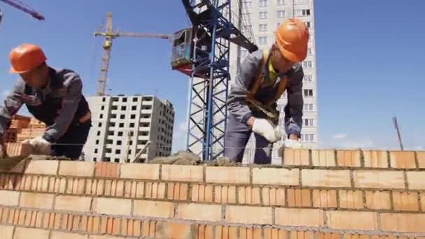 Μινσκ, Λευκορωσία, 14 2018 Αυγούστου-οι οικοδόμοι χτίζουν ένα κτίριο διαμέρισμα τούβλων. Οικοδόμος βιομηχανικό κοντινό-up εργαζόμενος τοποθετεί τούβλα σε ένα εργοτάξιο. — Αρχείο Βίντεο