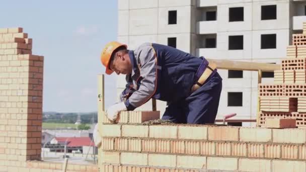 Μινσκ, Λευκορωσία, 14 2018 Αυγούστου-πολυκατοικία κατασκευή τούβλων. Ο εργάτης βάζει τούβλα σε ένα εργοτάξιο. Βιομηχανικός — Αρχείο Βίντεο
