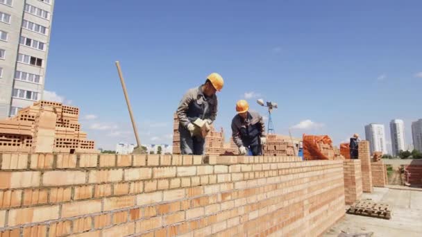 Minsk, Belarús, 14 de agosto de 2018 - Los constructores están construyendo un edificio de apartamentos de ladrillo industrial. Trabajador pone ladrillos en un sitio de construcción. Trabajos de ladrillo — Vídeo de stock