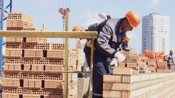 Mińsk, Białoruś, sierpień 14 2018-Budowa budynku apartamentowego z cegły. Pracownik kładzie cegły na placu budowy. Cegły przemysłowe — Wideo stockowe