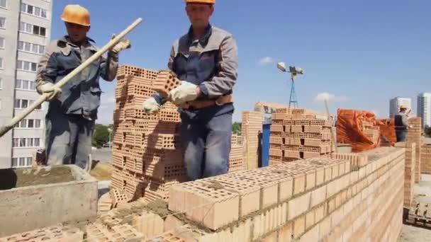 Μινσκ, Λευκορωσία, 14 2018 Αυγούστου-οικοδόμοι που εργάζονται σε πολυκατοικία κτίριο του τούβλου. Ο εργάτης βάζει τούβλα σε ένα εργοτάξιο. Βιομηχανικός — Αρχείο Βίντεο