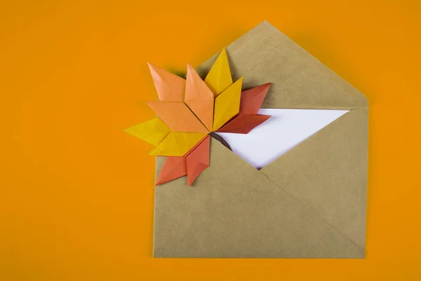 Origami papercraft autumn concept fallen leaves letter in an envelope on a plain background handmade craft art close up
