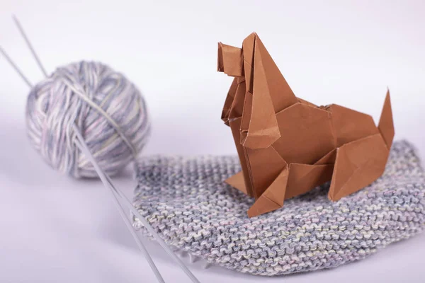 Selbstgebasteltes Origami-Konzept für ein gemütliches Zuhause - ein Hund mit Wollknäueln sitzt auf einer Peitsche. handgeschöpftes Kunstpapier aus Nahaufnahme im Studio. — Stockfoto
