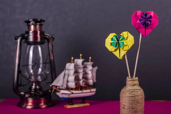 Concept of love handmade papercraft origami crafted colored paper heart close-up shot in studio with lamp and boat — Stock Photo, Image