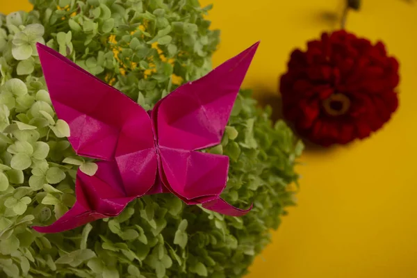 Origami farfalla su un cespuglio verde in un cesto su uno sfondo colorato bellissimo bouquet studio vicino colpo fatto a mano — Foto Stock
