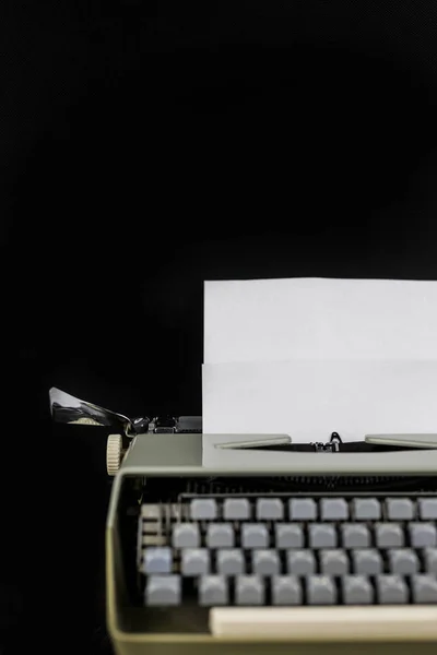 Psací stroj na černém pozadí s bílým papírem s prázdným prostorem. Pracovní plocha spisovatele nebo autora. Koncepce idejí. — Stock fotografie