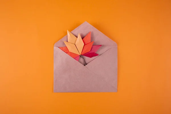 Origami papercraft autumn concept fallen leaves letter in an envelope on a plain background handmade craft art close up