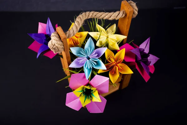 Flores de papel de colores hechos a mano origami ramo de papel arte artesanal en una cesta con hierba en el estudio sobre fondo oscuro — Foto de Stock