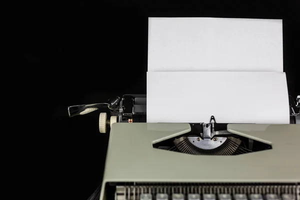 Typewriter on the table on a black background with white paper with empty space. Workplace of the writer or author. New life Concept. — Stock fotografie