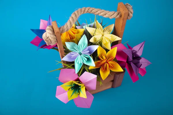 Flores de papel de colores hechos a mano origami ramo de papel arte artesanal en una cesta con hierba en el estudio sobre fondo acuático de color — Foto de Stock