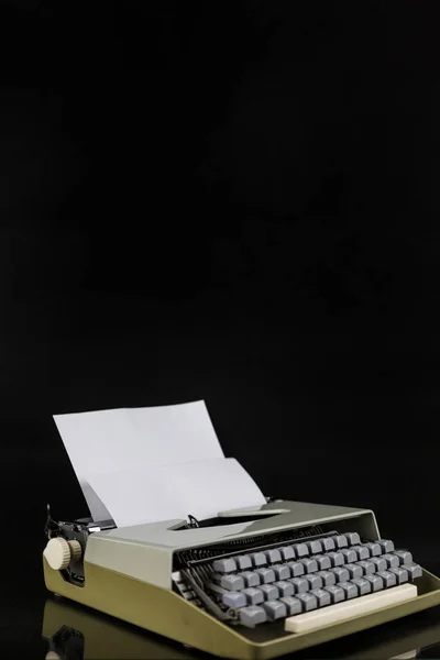 Typewriter on the table on a black background with white paper with empty space. Workplace of the writer or author. clean sheet concept